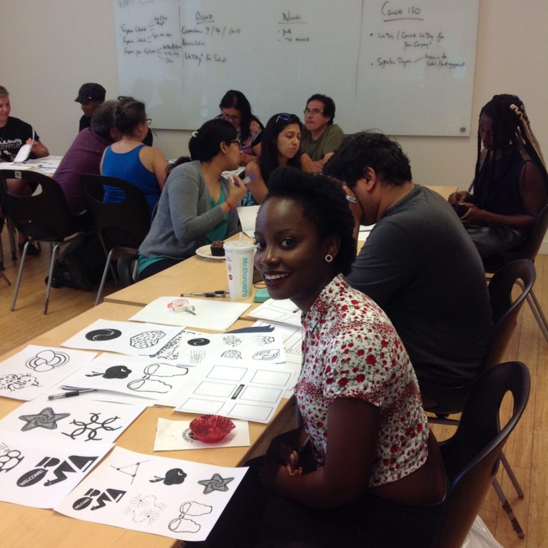 Photograph of a group designing with one person facing the camera and smiling in foreground