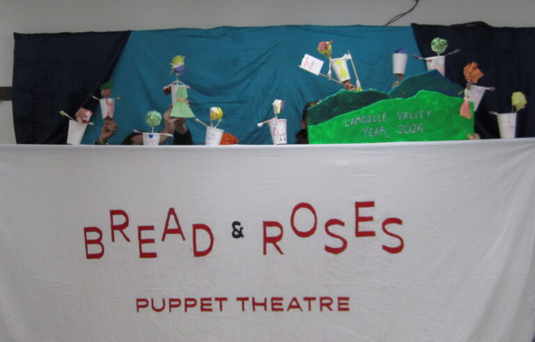 Group photo of 10 puppets behind a banner that reads "Bread & Roses Puppet Theatre"